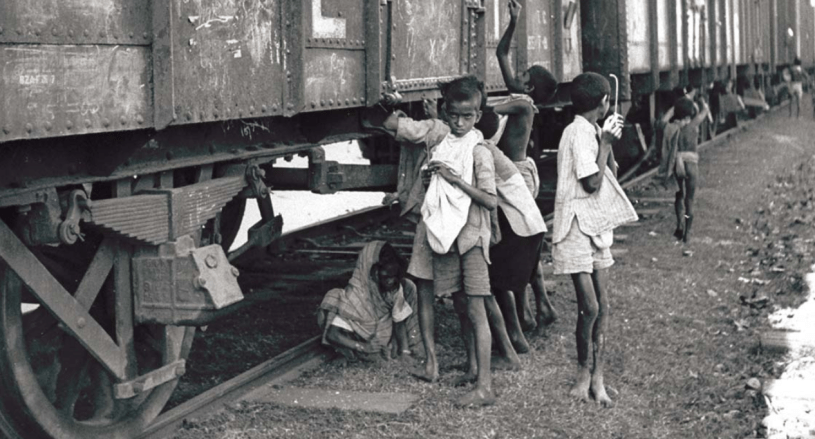 Children trying to pierce bags of grain in stationary train carriages, Bengal, 1943