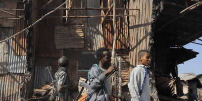 Residents and militias stand next to houses destroyed by an airstrike