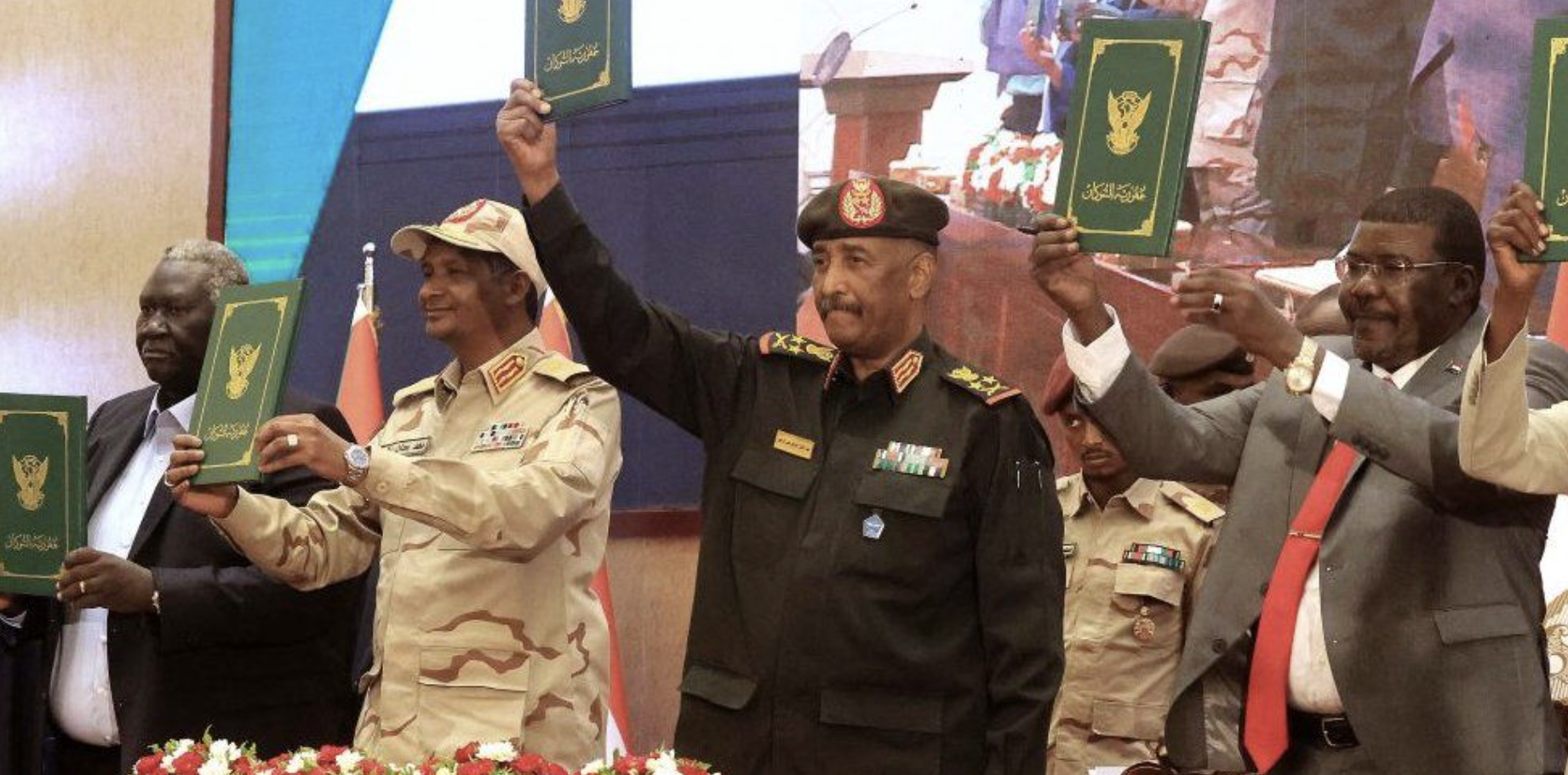 Sudan's Army chief Abdel Fattah al-Burhan (C R) and paramilitary commander Mohamed Hamdan Dagalo (C L) lift documents alongside civilian leaders