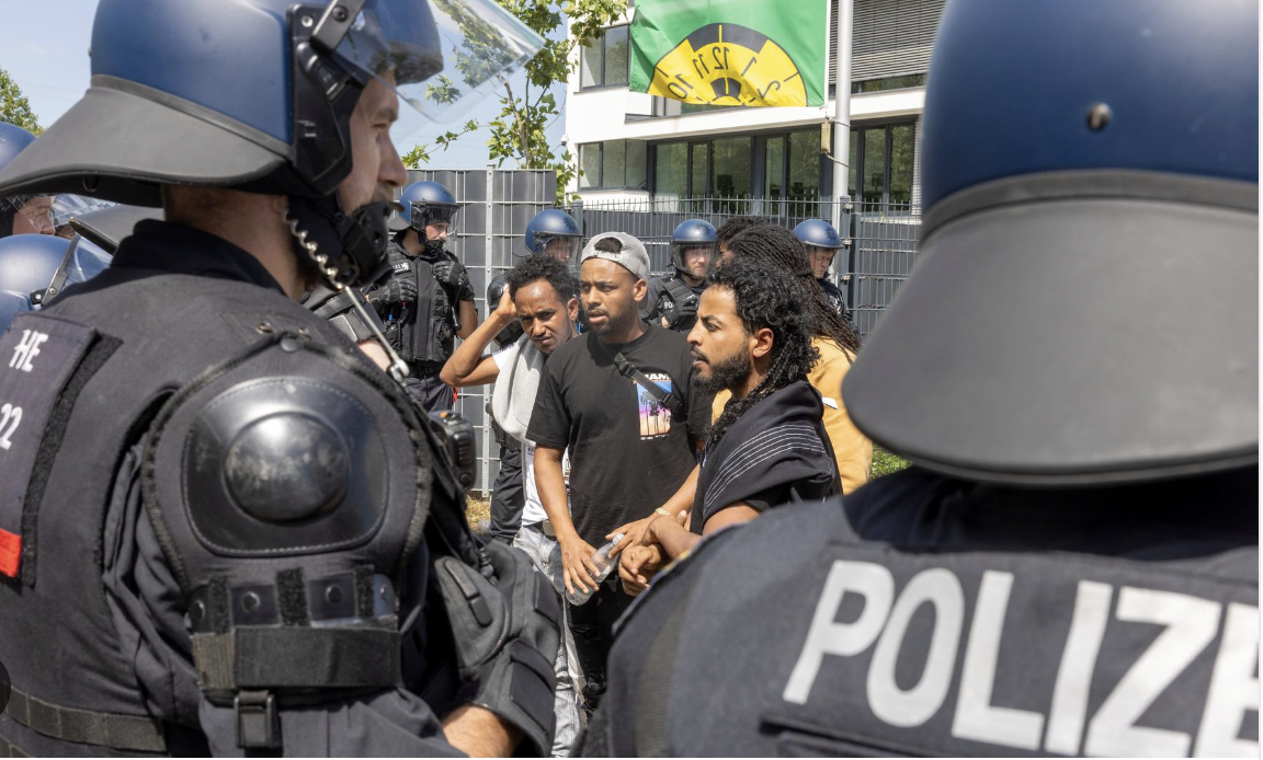 A group of counter-demonstrators from the Eritrea Festival stand on the street and are stopped by police officers
