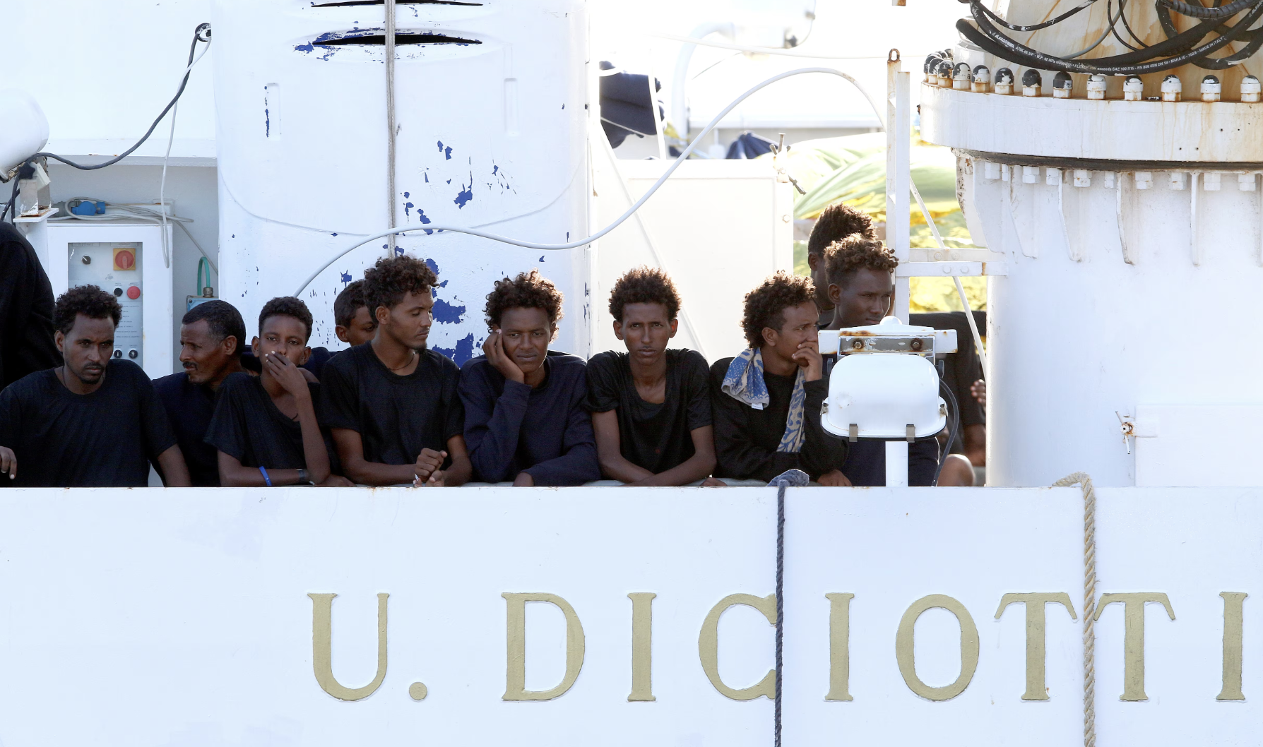 Migrants wait to disembark from the Italian coast guard vessel "Diciotti" at the port of Catania