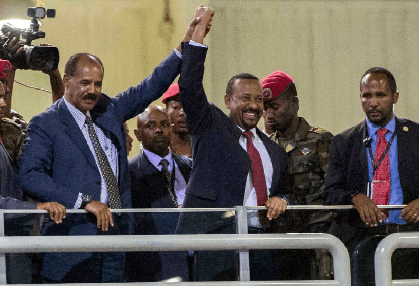 Eritrean President Isaias Afwerki and Ethiopian Prime Minister Abiy Ahmed, center, raise arms together in celebration before a crowd in Addis Ababa, Ethiopia, July 15, 2018