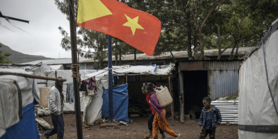 Internally displaced persons (IDPs) walk past the Tigrayan flag at the Tshehaye IDPs camp in Shire,Tigray region, on 16 July 2024. © Michele Spatari/AFP