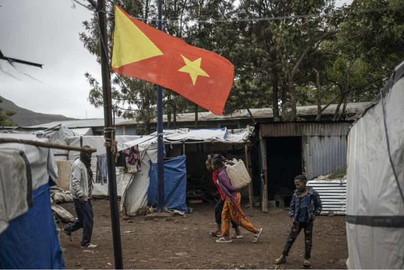 Internally displaced persons (IDPs) walk past the Tigrayan flag at the Tshehaye IDPs camp in Shire,Tigray region, on 16 July 2024. © Michele Spatari/AFP